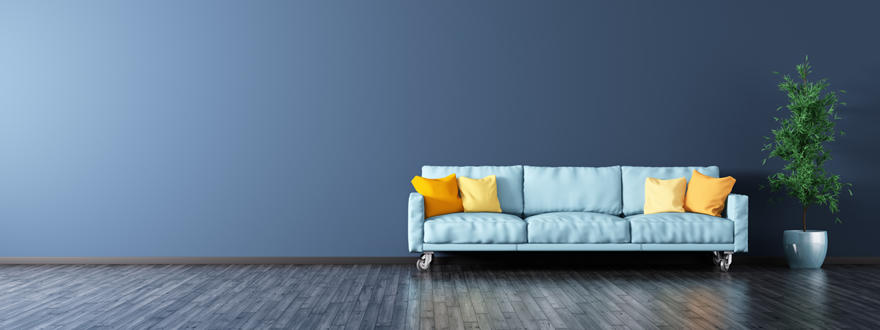 Empty room with wooden floor and wall, featuring a blue sofa.